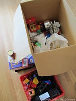 Cardboard box with vintage style play kitchen utensils including metal scale, wooden items, and boxed board games partially visible below.