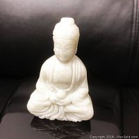 Front view of the white jade carved resting Buddha figure, showing facial and robe details