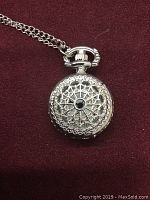 Front view of the silver tone watch pendant featuring intricate filigree and black stone centerpiece.
