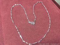 Full view of the twisted sterling silver necklace laid out on a red velvet background showing length and clasp.