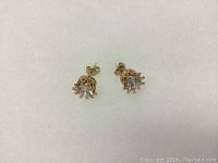 Clear photo of both earrings showing the front and side detailing of the gold plated setting and clear gemstones.