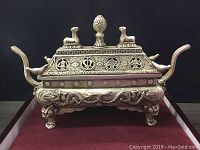 Front view of incense burner on red velvet tray against black background