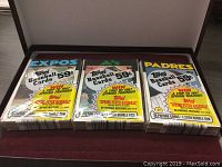 Three unopened 1985 Topps baseball card packs featuring Expos, A's, and Padres teams, each priced at 59 cents. Visible packaging shows promotion for trip to 1987 spring training.
