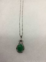 Front view of the green jade pendant with the silver setting and chain.