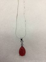 Front view of red jade tear drop pendant hanging from 925 silver chain