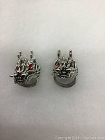Front view of the two silver dragon head rings showing detailed faces and red stone eyes.