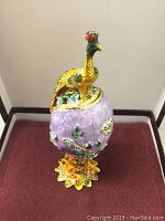Closed Faberge inspired peacock enamel egg showing the peacock figure and floral decorated egg.
