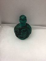 Front view of green carved snuff bottle with dragon design.