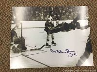 Black and white 11x14 photograph showing Bobby Orr's flying goal moment with facsimile autograph in blue ink.