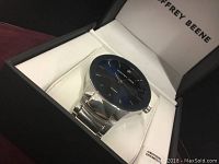 Geoffrey Beene watch showing the dial, diamond markers, and metal band inside the original box.