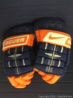 Pair of blue and orange Bauer Nike hockey gloves showing autographs on each glove.