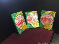 Photo of three unopened 1984 O-Pee-Chee Major League Baseball card packs in green packaging with special offer stickers.