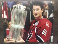 Canvas nylon print showing Mario Lemieux in a red Canada Cup hockey jersey holding a large trophy, with a facsimile autograph in black ink.