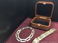 Both bracelets and wooden box displayed on burgundy surface