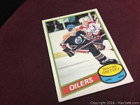 Front view of 1980 Wayne Gretzky O-Pee-Chee hockey card showing Wayne Gretzky skating with the Edmonton Oilers in a black jersey, with name and team