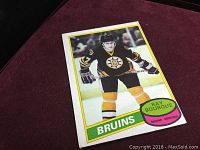 Front side of the 1980 Ray Bourque rookie card showing the player in Bruins jersey with colorful border and name.
