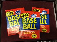 Three unopened packs of 1984 Fleer Baseball cards in original colorful packaging.