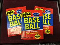 Three unopened packs of 1984 Fleer Baseball cards in red, blue, and yellow packaging, front view.