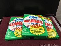 Three sealed 1984 Topps Major League Baseball card packs with green packaging and baseball graphic on front.