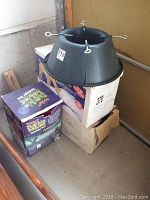 Christmas tree stand on top of boxes with Halloween decoration box visible