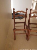 Two wooden chairs without seats positioned close together, visible decorative backrest design and spindle legs with rounded finials.