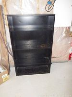 Front view of the black metal shelving unit showing five shelves with visible wear and some rust.