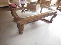 Side view of ornate glass top coffee table showcasing carved wooden legs and stretcher base