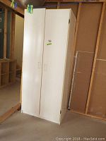 Front view of white cabinet closet with two doors showing handles and slight wear on the surface