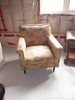 Front view of the upholstered armchair showing floral fabric and cushioned armrests.