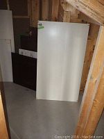 Photo of white and dark brown cabinet panels stacked in unfinished basement space
