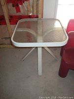 Full view of the square glass top patio side table showing textured glass surface and white metal frame.