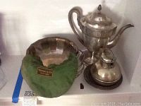 Photo showing the Tiffany & Co. sterling silver bowl with a green felt lining bearing the Tiffany label, along with silver plated basket, bowl, and pitchers.