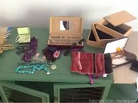 Overview of jewelry boxes, pouches, and some jewelry pieces laid out on a green surface