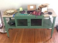 Full view of green wood and granite TV table with various small personal items on top.