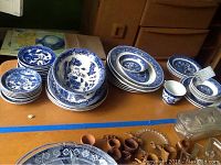 View of small and medium plates, bowls, and an oval serving dish with blue willow pattern designs