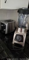 Vitamix blender and Krupps toaster on kitchen counter, shown powered off.