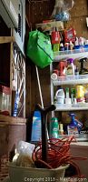 View of plastic shelving unit with assorted cleaning supplies and tools against basement pegboard wall
