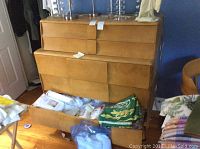 Front view showing five drawers, two upper smaller and three lower full-width. Lower drawer open revealing patterned liner.