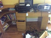 Front view of desk assembly showing attached corner bookshelf, drawers, and items on surface