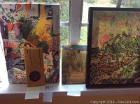 Three canvases placed on a window sill showing vibrant indoor and outdoor scenes with warm colors and abstract impressionist style.