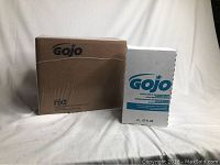 Image showing one large brown box and one white box of Gojo Ultra Mild Antimicrobial Lotion Soap refill, 2L size, on a white cloth background.