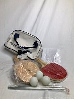 Ping pong set items including paddles, balls, net, poles, cork bases, and carry bag