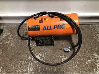 Front left view of orange All-Pro propane forced air heater with hose coiled on top