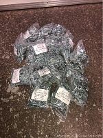 Large quantity of individually bagged zinc wood screws piled together on floor showing multiple labeled bags.