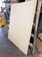 Two white pegboards, 46x54 inches each, leaning against a ladder in a storage or workshop environment.