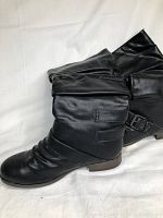 Side view of both boots highlighting the texture, slouched shaft and decorative buckles on black mid-calf boots.