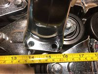 Close-up view of caster mounting plate with measuring tape showing about 4 inches width between holes.