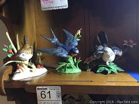 Three Lenox porcelain bird figurines displayed on a wooden surface showing all birds together