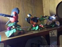 Three Lenox porcelain bird figurines including Vermilion Flycatcher, Baltimore Oriole, and European Goldfinch on wooden shelf.