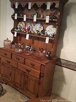 Front and side view of the full two-piece buffet hutch showing wooden shelves with plate racks, drawers, and cabinet doors with metal hardware.